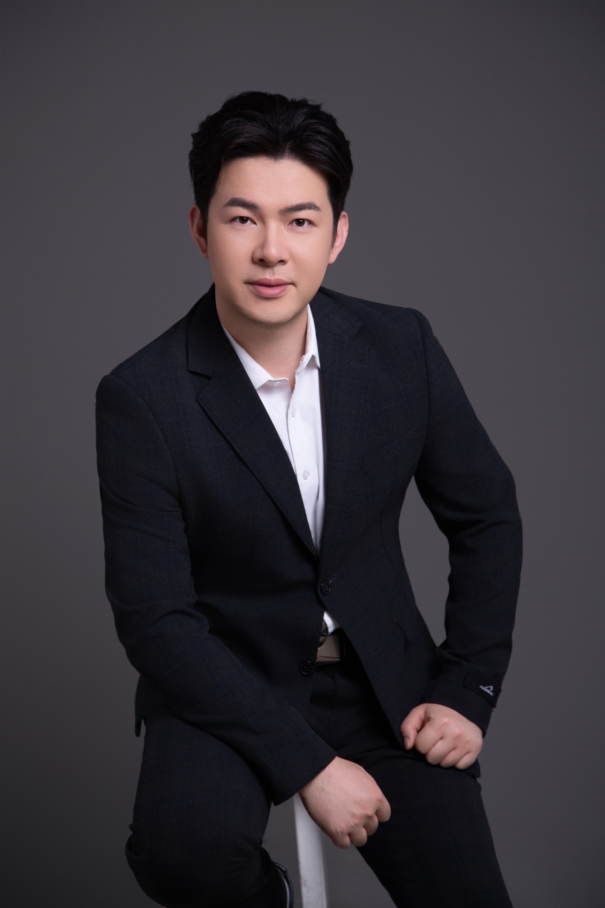 李哈利身穿深色西裝，坐姿直視鏡頭